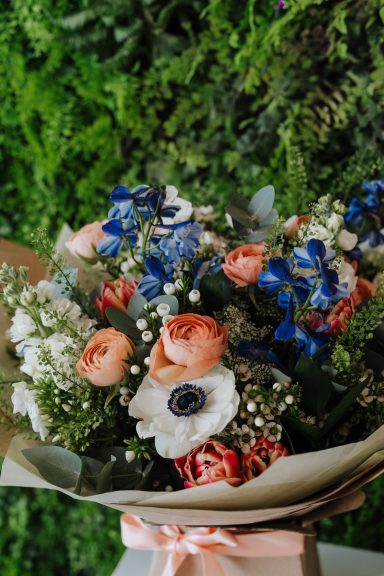 A bouquet featuring roses, anemones, and mixed greenery against a blurred background.