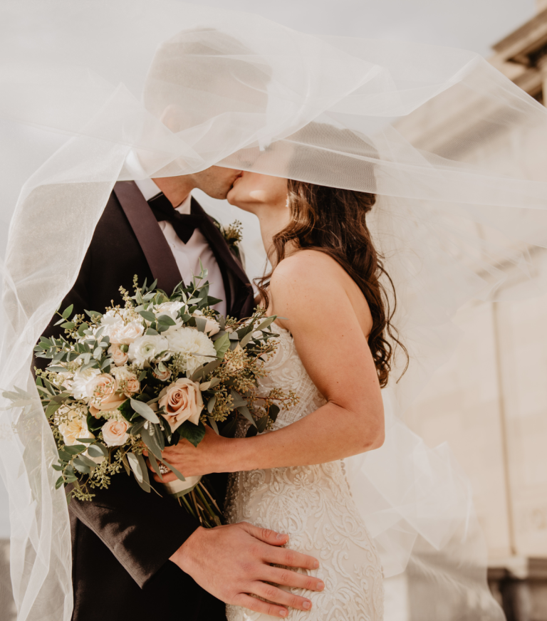 Bride holding pastel bouquet kissing groom